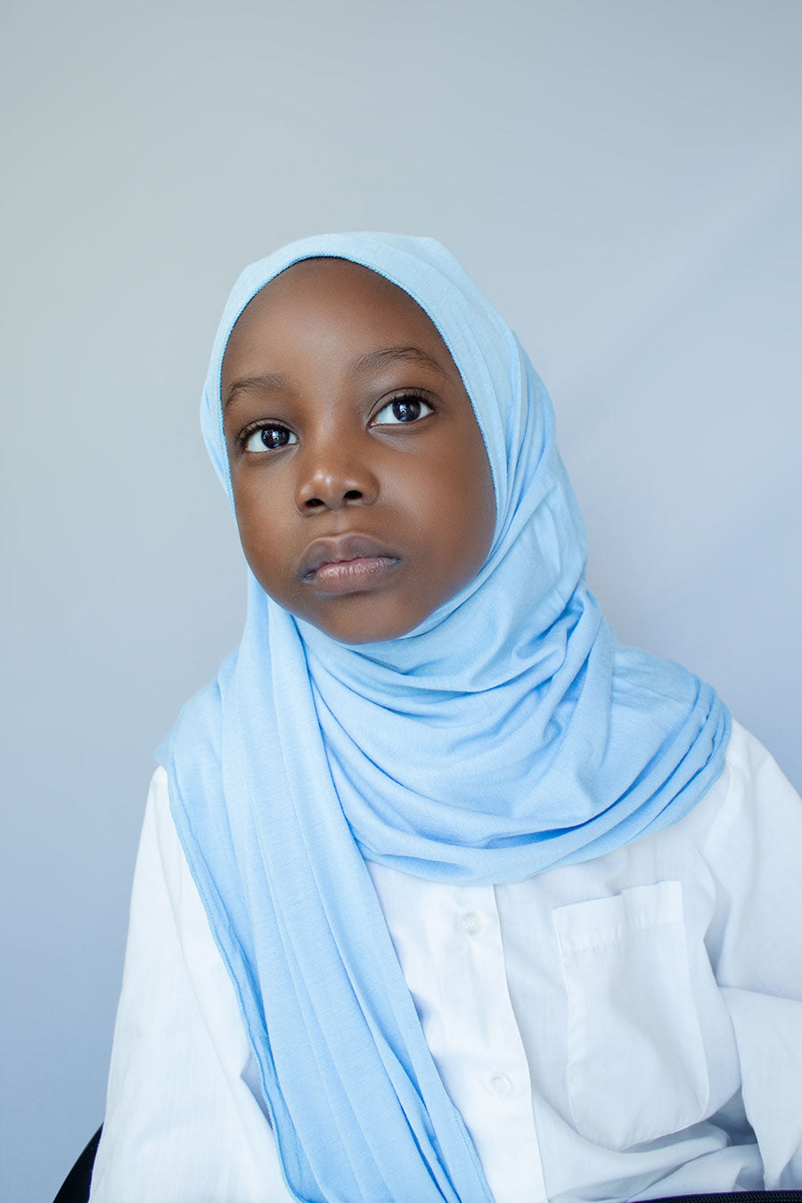 a little girl is wearing blue hijab
